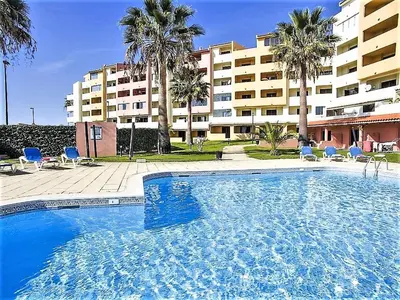 a large swimming pool with blue chairs and a building at Belavista Centre - Albufeira in Albufeira