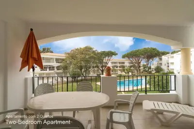 a balcony with a table and chairs and a pool at Akisol Vilamoura Pine in Quarteira
