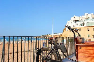 a bike parked next to a fence next to the beach at Charming Blue Albufeira in Albufeira
