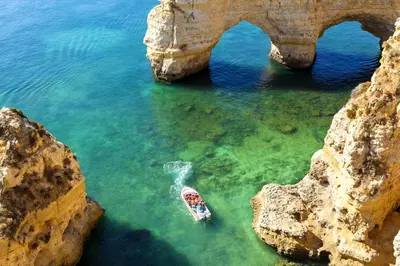 a boat in the water next to an arch in the ocean at Charming Blue Albufeira in Albufeira