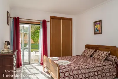 a bedroom with a bed and a sliding glass door at Akisol Albufeira Falesia IV in Albufeira