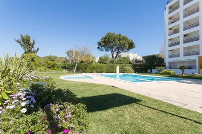 a garden with a swimming pool and a building at FLH Vilamoura Central Flat in Quarteira