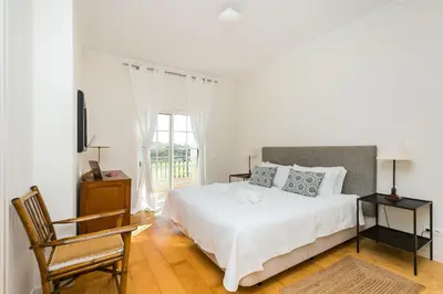 a bedroom with a bed and a chair and a window at Villa Formosa Golf in Quinta do Lago