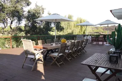 a wooden deck with a table and chairs and umbrellas at Villa Formosa Golf in Quinta do Lago
