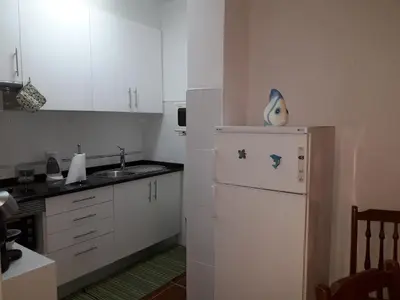 a kitchen with a white refrigerator and a sink at Apartamento Quarteira T1 in Quarteira