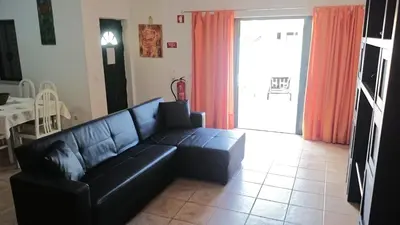 a living room with a black leather couch in front of a door at Holiday House in Albufeira