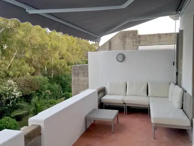 a patio with two white chairs and a table at Casa Balaia in Albufeira