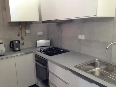 a kitchen with white cabinets and a stove and a sink at Casa Balaia in Albufeira