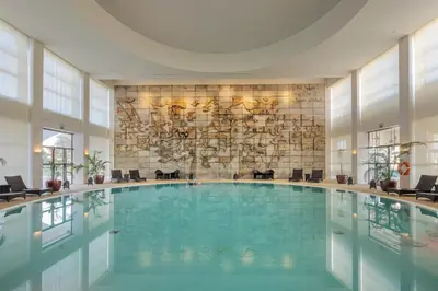 a bedroom with a bed and a chair and a mirror at Crowne Plaza Vilamoura - Algarve by IHG in Vilamoura