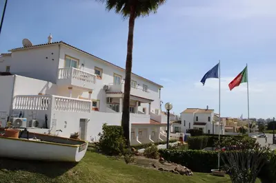 a house with two flags and a boat in front of it at Agua Marinha ROSA- Hotel in Albufeira
