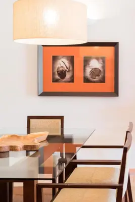 a dining room with a glass table and an orange wall at Birdsong Vila Sol Village in Vilamoura