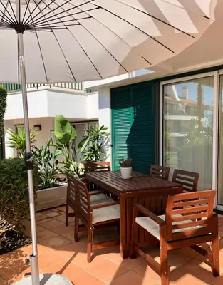 a wooden table and chairs with an umbrella on a patio at Birdsong Vila Sol Village in Vilamoura