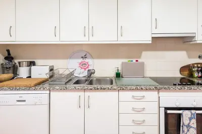a kitchen with white cabinets and a sink at Birdsong Vila Sol Village in Vilamoura