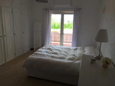 a bedroom with a bed and a window and a table at Cegonha Villa powered by Cegonha Resort- Private swimming pool & air con in Albufeira
