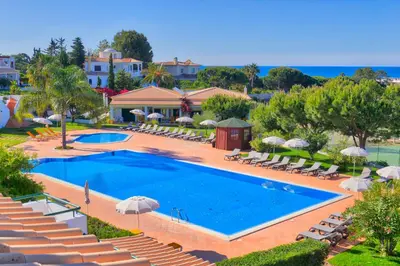 a swimming pool with chairs and umbrellas at a resort at Moradias Villas Rufino in Albufeira