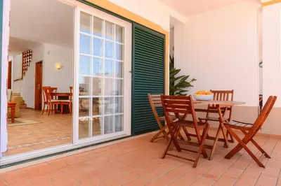 a patio with a table and chairs on a porch at Moradias Villas Rufino in Albufeira