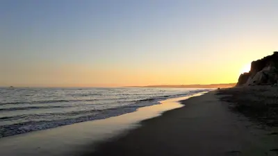 a beach with the sun setting over the ocean at Ritta's house in Albufeira