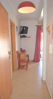 a hallway with a television and a table and a chair at Ritta's house in Albufeira