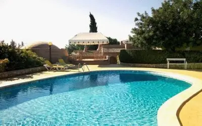 a large blue swimming pool in front of a house at Lageado Park in Albufeira