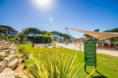 a sign in a park with a playground in the background at Boa Vida in Quarteira