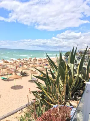 a beach with umbrellas and chairs and the ocean at Boa Vida in Quarteira