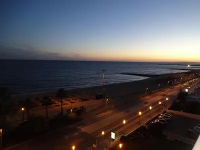 a view of a street at night with the ocean at ACR Holiday Apartment in Quarteira