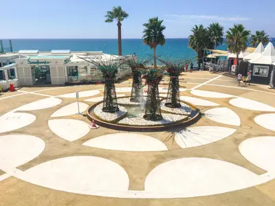a fountain with palm trees and the ocean in the background at Casa das Flores in Vale do Lobo