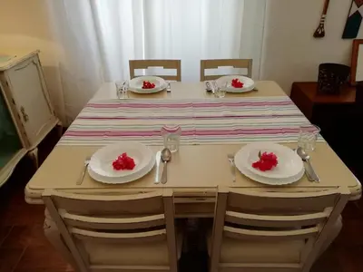 a table with white plates and red flowers on it at Casa da Guida in Albufeira
