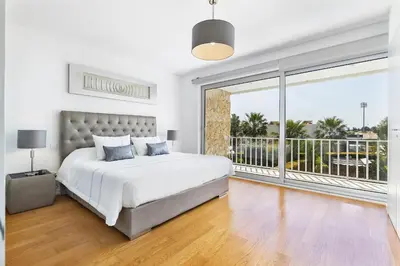 a white bedroom with a large bed and a balcony at Design Villa Pascoal in Albufeira