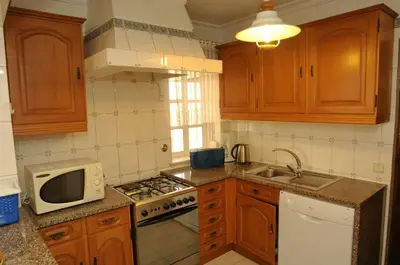a kitchen with a microwave and a stove top oven at Villa V4 com Piscina Privada a 400 metros da Praia in Albufeira
