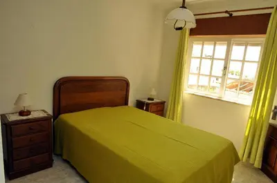 a bedroom with a green bed and a window at Villa V4 com Piscina Privada a 400 metros da Praia in Albufeira