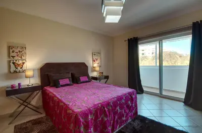 a bedroom with a purple bed and a large window at Spacious house with private pool in Albufeira in Albufeira