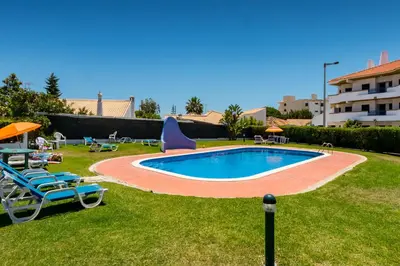 a swimming pool in a yard with chairs and umbrellas at Camilla apartment in Albufeira