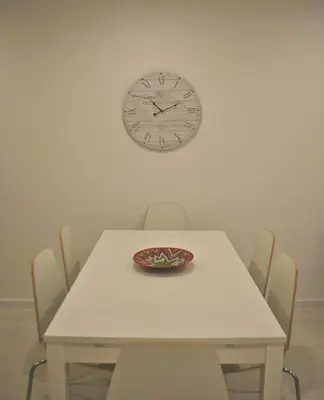 a table with chairs and a clock on the wall at Stay Inn Albufeira - 303B Apartment in Albufeira