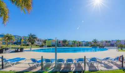 a swimming pool with blue chairs and palm trees at Apartamentos da Orada by Garvetur in Albufeira
