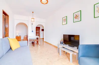 a living room with a blue couch and a tv at AL - Apartamento Girassol in Quarteira