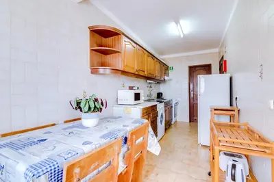 a kitchen with wooden cabinets and a white refrigerator at AL - Apartamento Girassol in Quarteira