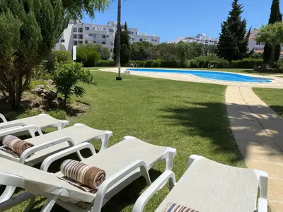 a row of white lounge chairs in a park at Bogart at Casablanca by OCvillas in Albufeira