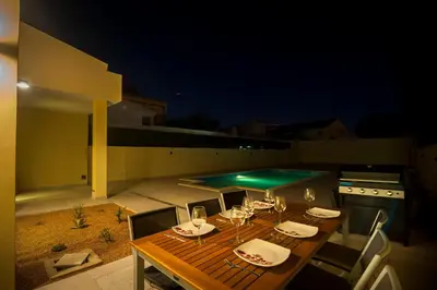 a wooden table with wine glasses and a swimming pool at villa Aqua-Jacuzzi-heatable pool-sauna-gym-snooker in Albufeira