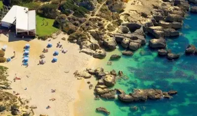 a beach with rocks and people in the water at The Albufeira Concierge - Modern Salgados in Albufeira