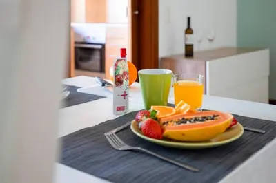 a plate of fruit on a table with a glass of orange juice at The Albufeira Concierge - Modern Salgados in Albufeira