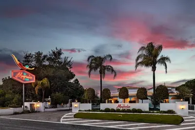 a view of a hotel with palm trees and a sunset at The Magnolia Hotel in Quinta do Lago