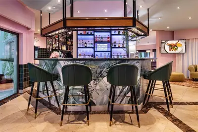 a bar in a restaurant with green bar stools at The Magnolia Hotel in Quinta do Lago