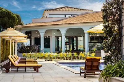 a resort with yellow chairs and tables and a pool at The Magnolia Hotel in Quinta do Lago