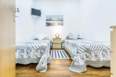 two beds in a room with white walls and wooden floors at Casa Laranjinha in Albufeira