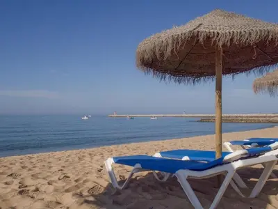 two lounge chairs and an umbrella on a beach at Paradise Quarteira in Quarteira
