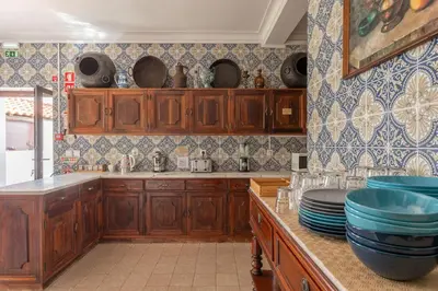 a kitchen with wooden cabinets and blue and white tiles at Casa dos Arcos - Charm Guesthouse in Albufeira