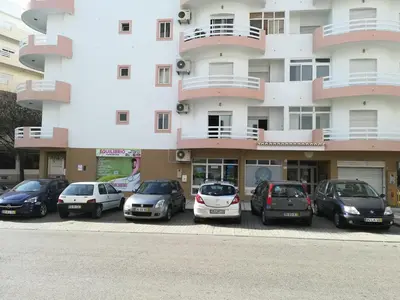 a group of cars parked in a parking lot in front of a building at Porque Você Merece in Quarteira