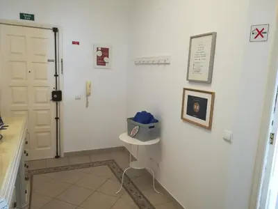 a hallway with a white wall with a table and a door at Porque Você Merece in Quarteira