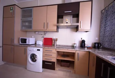 a kitchen with a washing machine and a microwave at Apartamentos Plaza - Albufeira in Albufeira